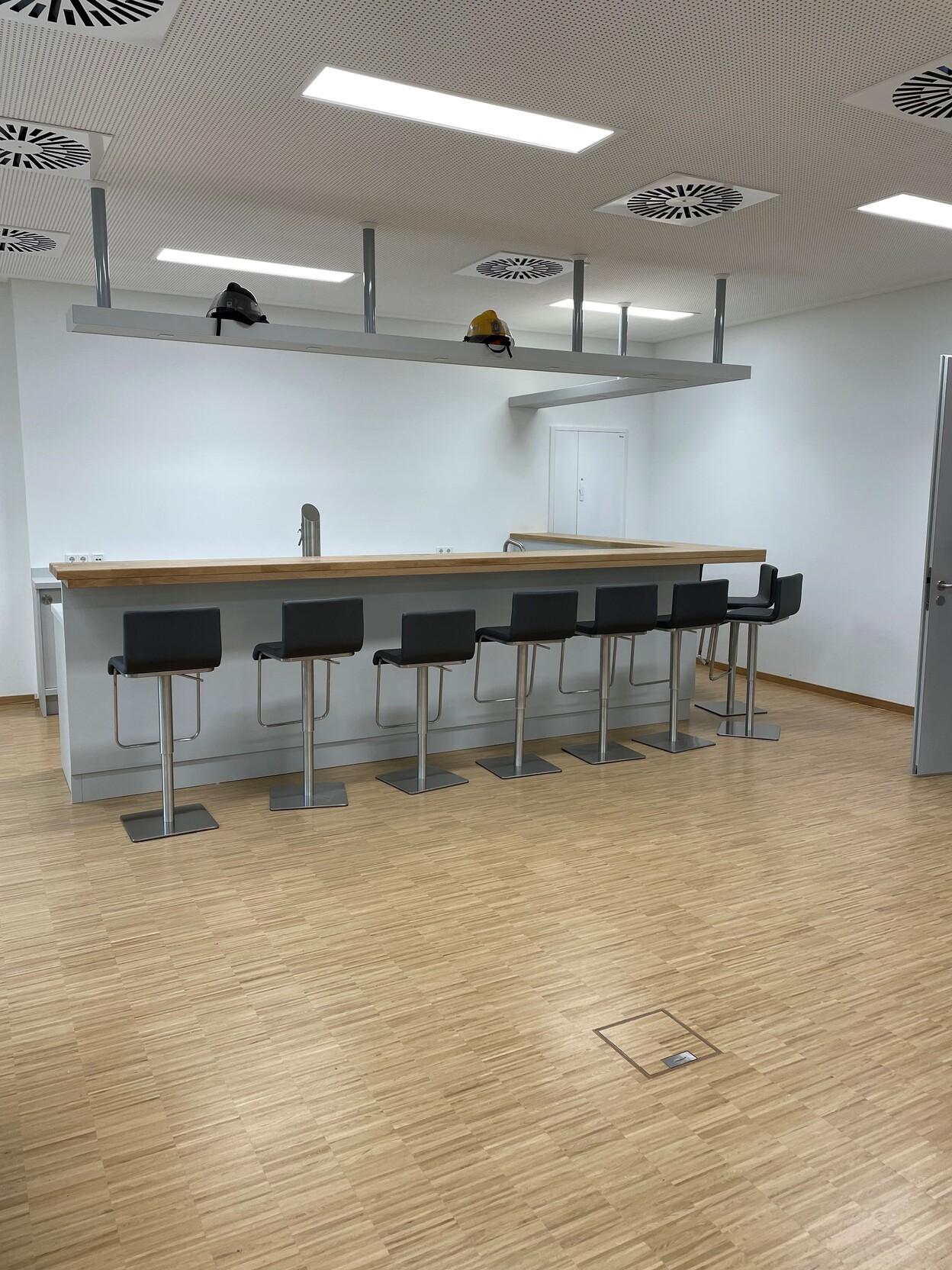 Individueller Möbelbau Tresen Moderner Tresen im individuellen Möbelbau mit Holzarbeitsplatte und Barhockern im Gemeinschaftsraum.