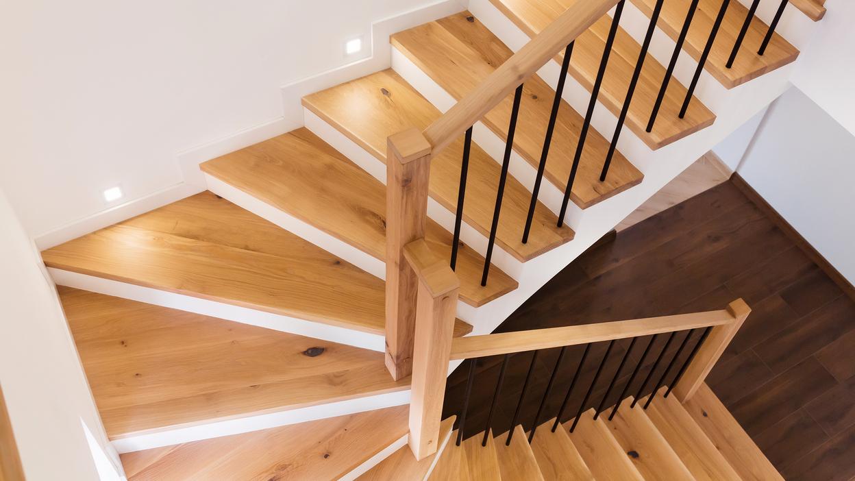 Exklusive Treppe nach Maß Elegante Treppe nach Maß aus Holz mit schwarzem Metallgeländer und integrierter LED-Beleuchtung.