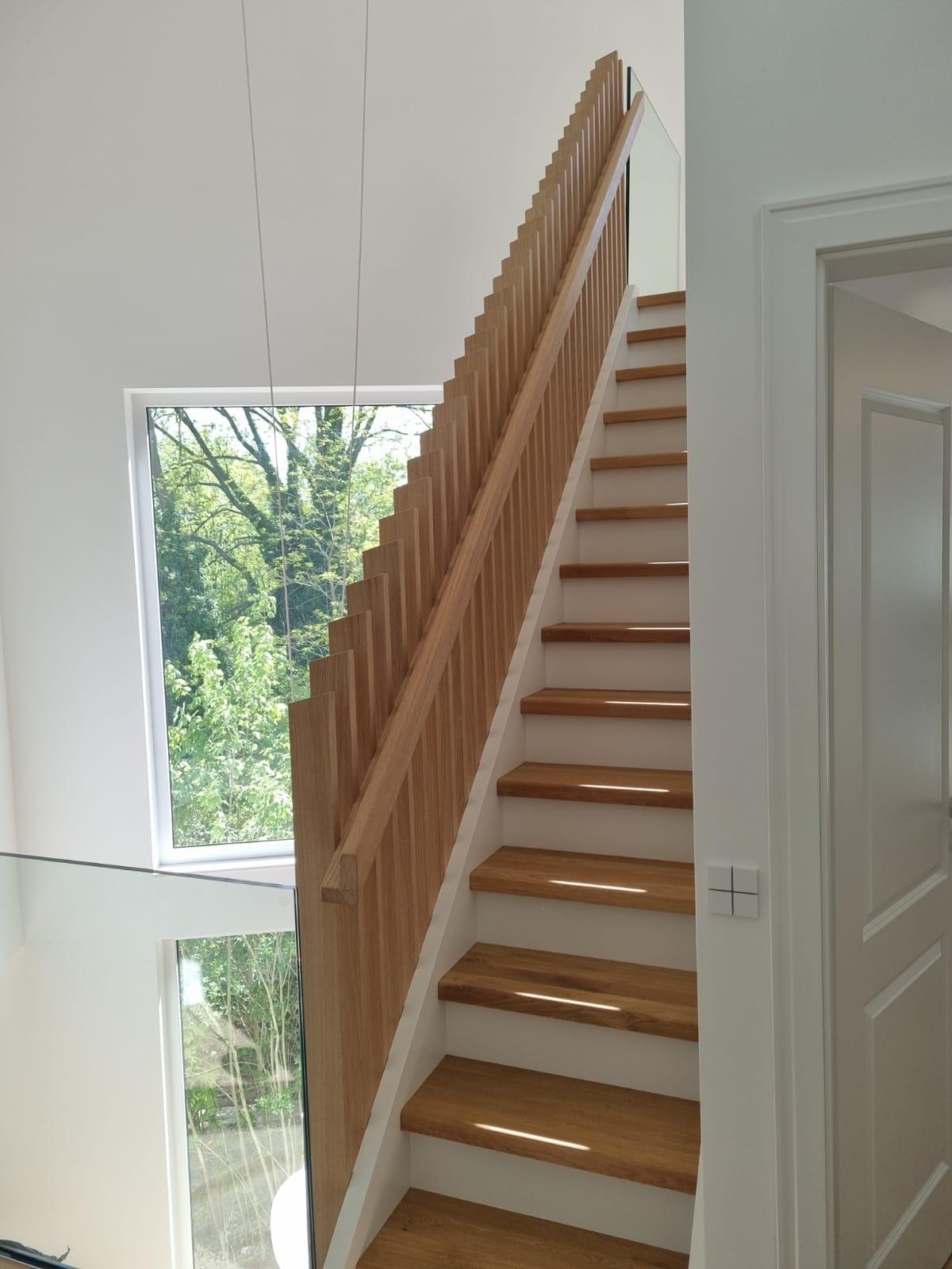 Moderne Treppe nach Maß Individuelle Holztreppe nach Maß mit geradlinigem Geländer und großem Fenster im Treppenhaus.