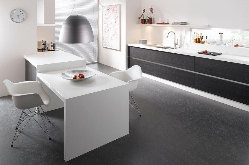 Impression einer einzeiligen K&uuml;chengestaltung in schwarz-wei&szlig; mit Esstisch f&uuml;r Zwei